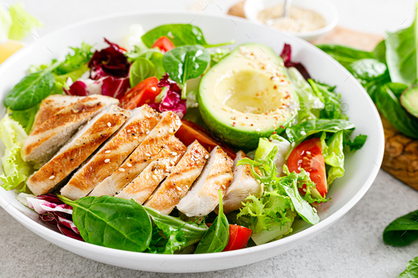 Grilled Chicken Meat And Fresh Vegetable Salad Of Tomato, Avocado, Lettuce And Spinach. Healthy And Detox Food Concept. Ketogenic Diet. Buddha Bowl Dish On White Background