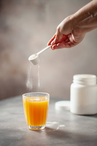 Powder Collagen Puts Hand In Glass Of Citrus Juice.