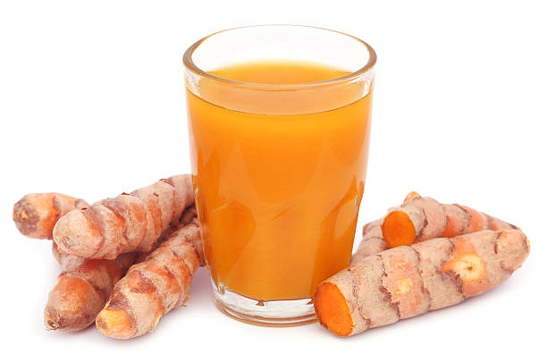 Fresh Turmeric With Extract In A Glass Over White Background