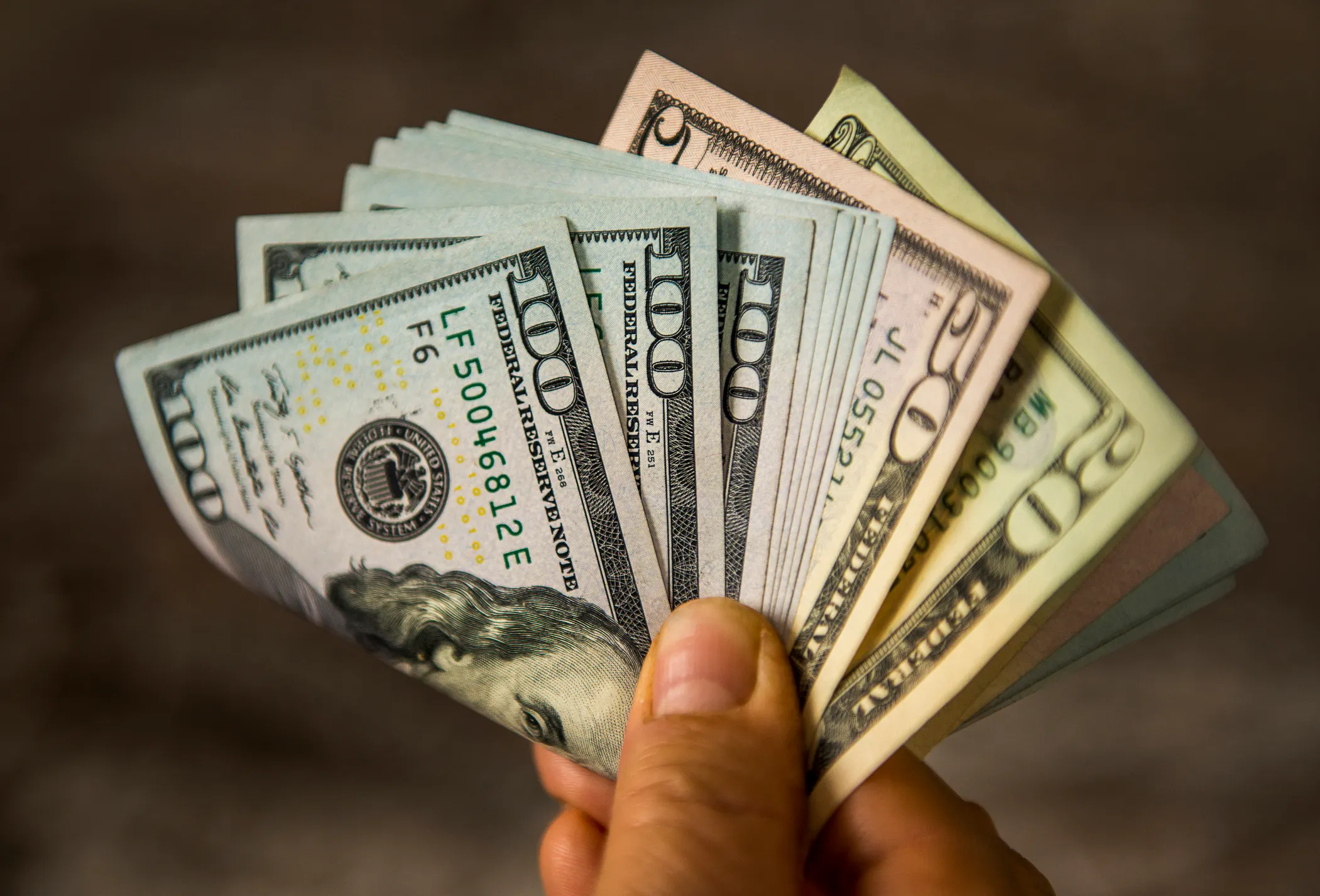 76585349007 76326097007 Personholdingcashbillsmoneyhundreddollarfiftydividendincomeinvestretirespendgetty