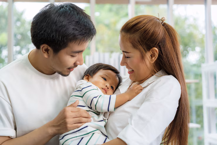 Asian Father Mother Are Hugging 9 Months Baby Son Sofa They Are Smiling Warm Touching Baby With Love Living Room Home_73503 2698