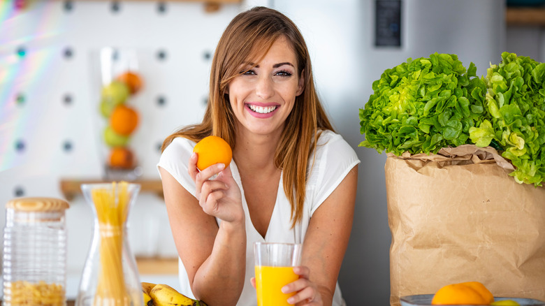 Young,Joyful,Woman,Drinking,Orange,Juice,And,Standing,Near,A