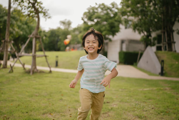 Playful Boy Running Along In Park On Free Day.
