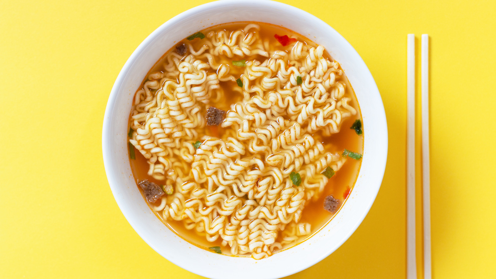 Instant Noodle Soup In A White Bowl On Yellow Background Top View.